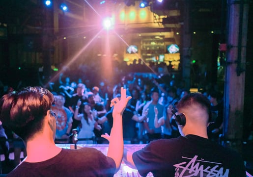 Two DJs facing a lively crowd, reflecting the driving energy of the drum rhythms essential in Understanding the Core Components of an EDM Song.