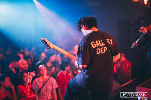 A musician playing the bass guitar, highlighting the essential bassline element that provides the groove and rhythmic foundation in Understanding the Core Components of an EDM Song.