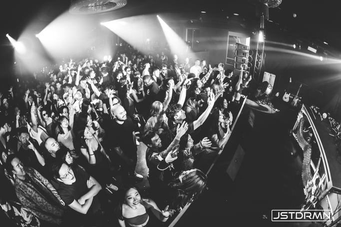 A black-and-white photograph of a crowd immersed in the music, symbolizing the exhilarating dance floor experience and the transformative journey described in Understanding the Core Components of an EDM Song.